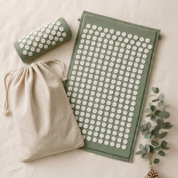 Green acupressure mat and neck pillow set with white lotus spike points, displayed with black carry bag on marble surface — back pain relief wellness gift for women
